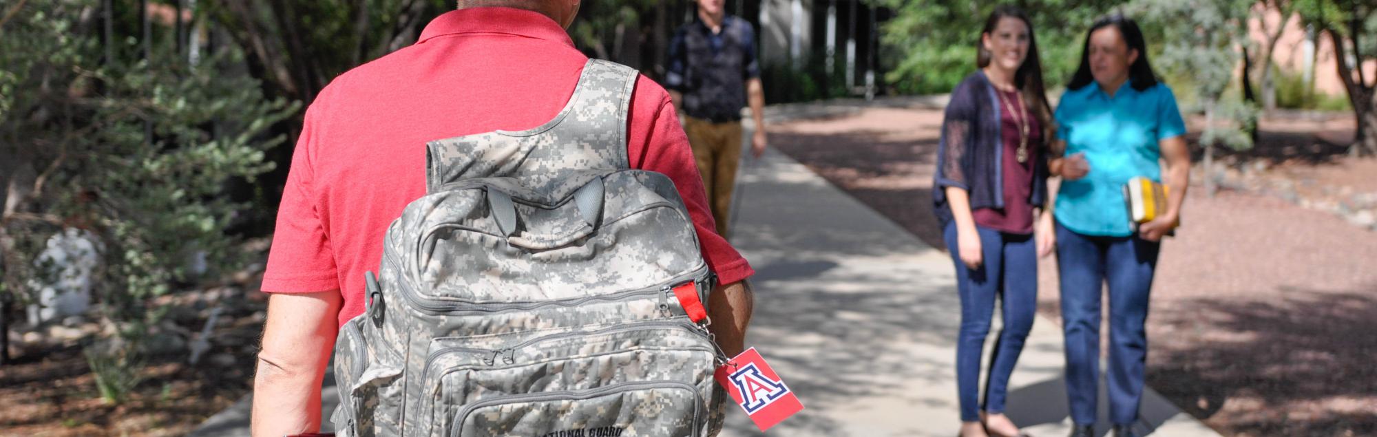 UA student walking with army backpack